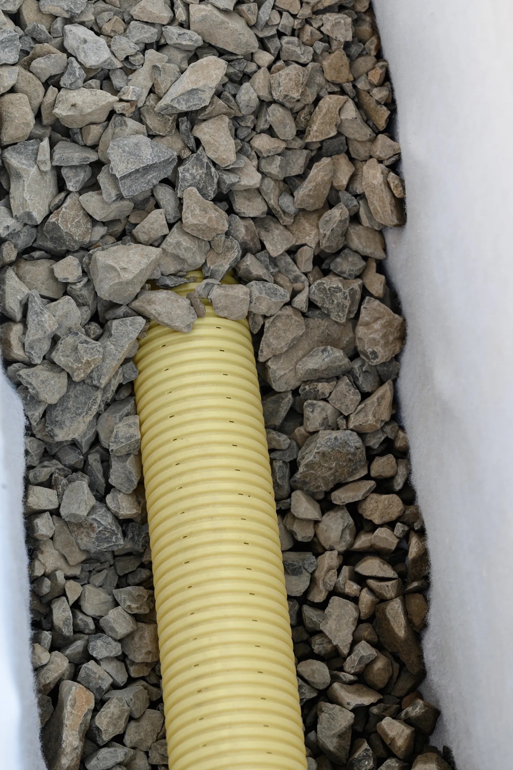 French drain perforated pipe and gravel trench installation in DFW yard