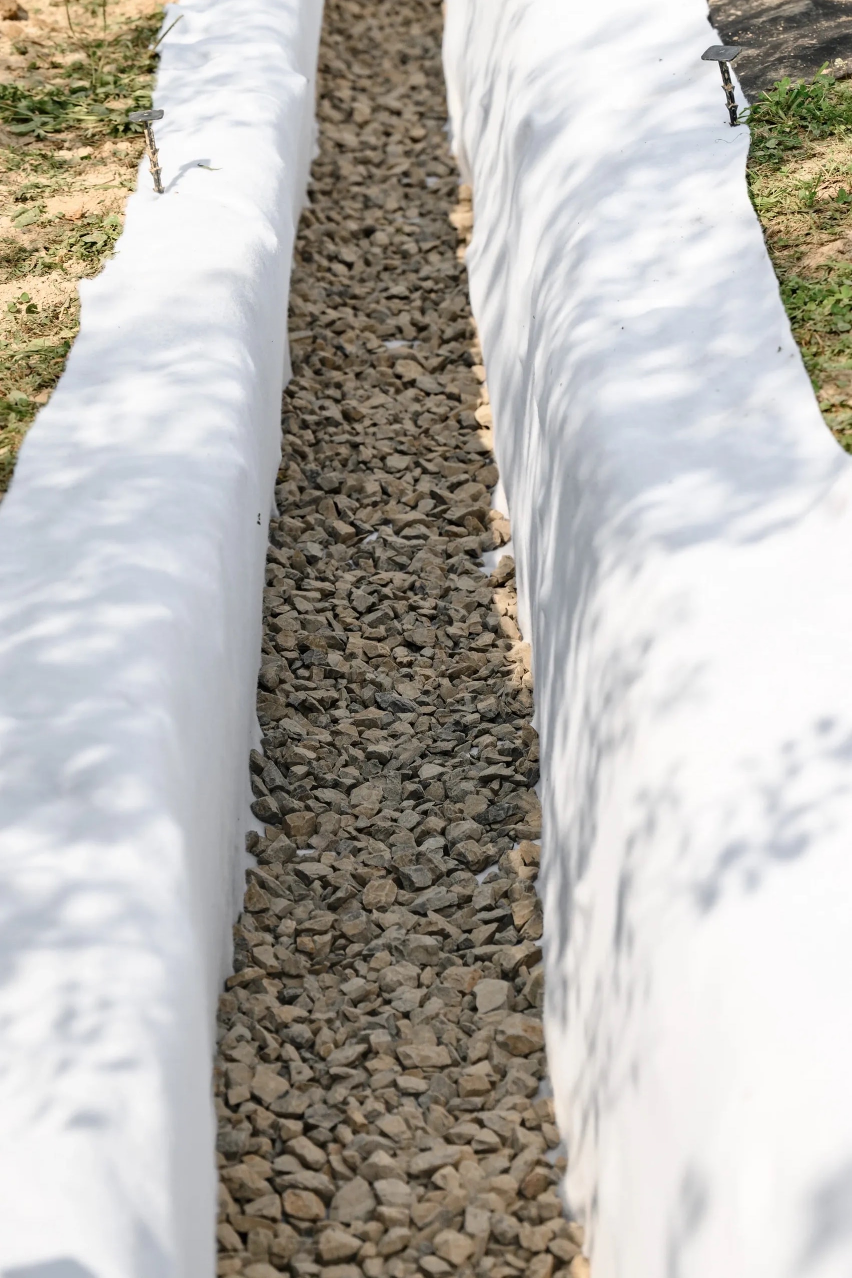 Retaining wall drainage system with gravel backfill and perforated pipe installation